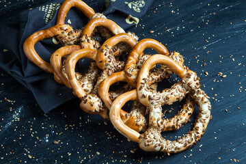 Fresh prepared homemade soft pretzels. Different types of baked bagels with seeds on a black background.