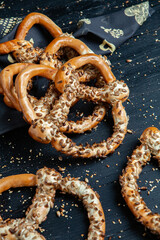 Fresh prepared homemade soft pretzels. Different types of baked bagels with seeds on a black background.
