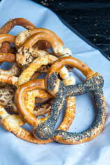 Fresh prepared homemade soft pretzels. Different types of baked bagels with seeds on a black background.
