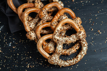 Fresh prepared homemade soft pretzels. Different types of baked bagels with seeds on a black background.