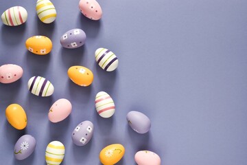 Colorful easter eggs on purple background. Yellow, pink and violet eggs. Copy space, Flat lay. Easter holiday concept. Traditional decoration for springtime holiday. Easter greeting card