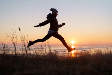 Woman silhouette jumping in natural beautiful sunset. Motivation