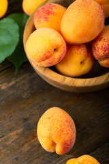 Delicious ripe apricots in a wooden bowl on the table close-up. Top view