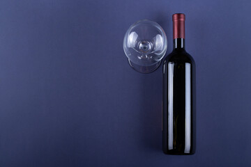 Bottle of red wine without a label and a glass empty on a purple paper background. Mockup drink with place for you label and text. Space for text.