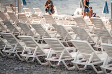 Several white sun loungers and an umbrella on a deserted beach. The perfect vacation concept.