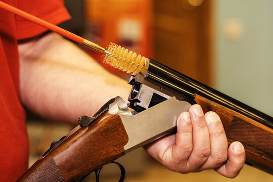 The process of cleaning a shotgun with a plastic brush. Caring for firearms with special tools. Close-up. Unrecognizable person