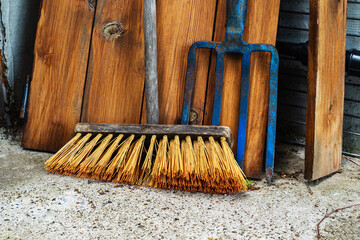An old floor brush and metal pitchfork are located in the utility room. Antique tools for household...