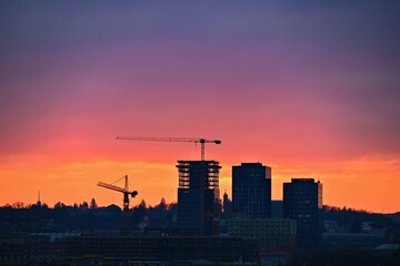 Construction of buildings with a crane, workers and construction machinery at sunset. Concept for construction and industry.