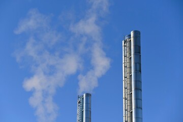 Steaming chimneys in the city. Concept for environment and industry. Background with blue sky.