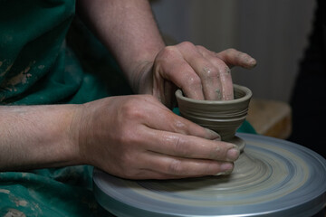 Potter at work. Hands of potter do a clay pot