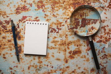 notes, lupa i długopis na blaszanym stole