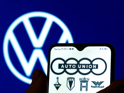 In this photo illustration, the Auto Union AG logo is seen displayed on a smartphone screen with a Volkswagen AG logo in the background.