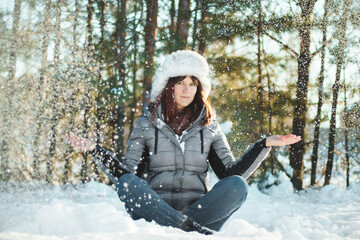 Woman doing yoga in lotus position in winter forest. Relaxation and meditation concept.