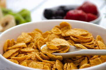 Corn flakes with fresh banana and kiwi, as well as fresh strawberries, blueberries. Healthy breakfast for the whole family.