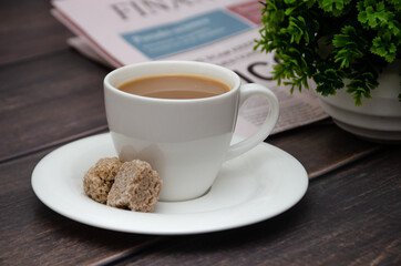 Aromatic coffee with cane sugar and morning newspaper on a wooden table.
