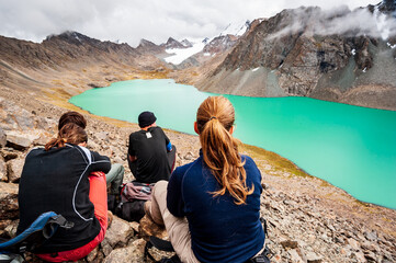 Group of trekker backpackers sitting relaxing at bank of Beautiful landscape of turquoise Ala-Kul...
