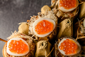 top view on delicious eggs stuffed with red caviar serving in golden shell in egg box