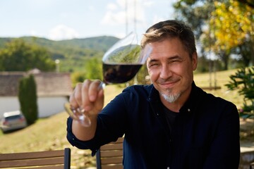 Man relaxing drinking tasting red wine outdoor in garden. Authentic and atmospheric moment.