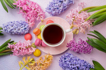 Fototapeta na wymiar Cup of tea with colorful macaroons and hyacinths, top view.