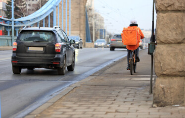 Kurier na rowerze jedzie mostem Grunwaldzkim we Wrocławiu, dostarcza jedzenie. 