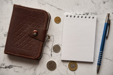 notes , długopis ,brązowy portfel i monety na marmurowym stole ,polski złoty	