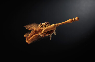 Fototapeta premium Cinnamon powder is poured out of the wooden spoon.