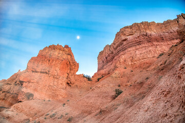 Aerial view of Bryce Canyon at summer sunset with moon in the sky. Overlook of orange colorful hoodoos red rock formations in Bryce.