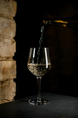 wine glass into which tasty white wine is poured from a bottle.