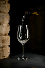 wine glass into which white tasty sparkling wine is poured from a bottle.