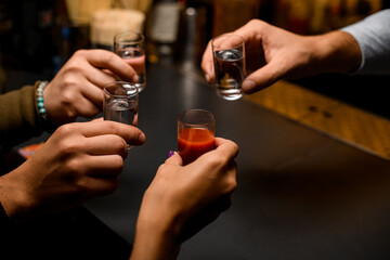 Male hands cheer with glasses of vodka and liqueur