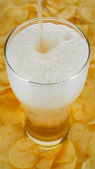 Pour beer in glass, foam flows down over. Beer and chips