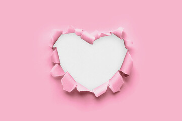 A paper hole with torn edges on a pink background. Through paper. A ragged hole in the shape of a...