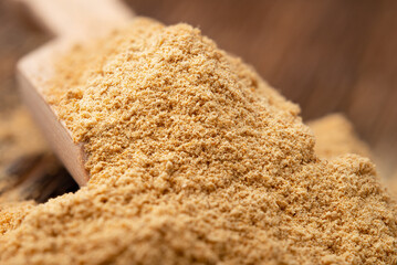 Dried ginger powder in a wooden scoop close up