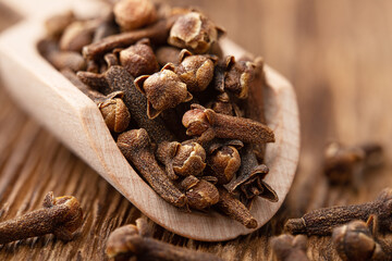 Whole cloves in a wooden scoop close up