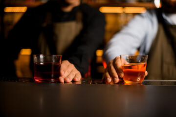 beautiful view of glasses with bright cocktails on the bar and males hands