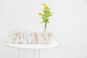 Candle holder in shape of word HOME and flowers on table