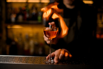 wine glass with booze stands on the bar and fiery flame is in the background