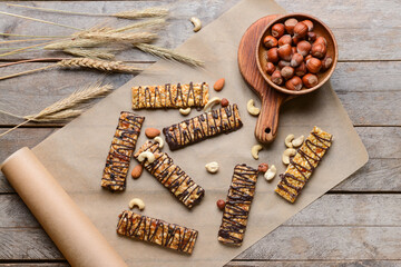 Parchment with tasty chocolate nut bars on wooden background