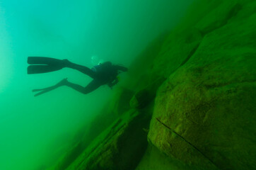 SCUBA diver exploring a cloudy inland lake with large boulders