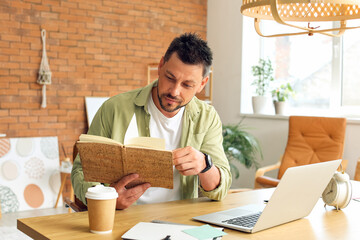 Fototapeta premium Handsome man working with notebook at table in office