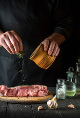 Cook prepares raw veal meat. Before baking, the chef adds a dry herbal seasoning to the beef. National dish is being prepared in the restaurant kitchen.