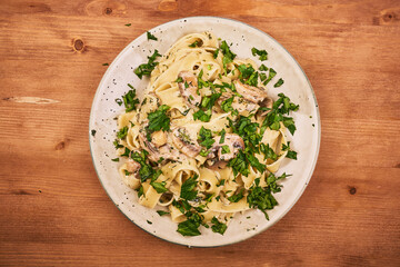 Fettuccine with mushroom sauce and fresh parsley in a plate, top view - classic italian pasta