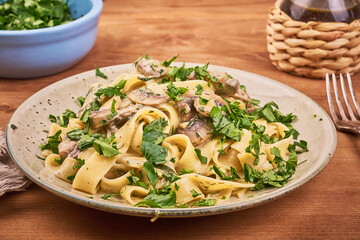 Fettuccine with mushroom sauce and fresh parsley in a plate, close-up - classic italian pasta