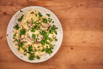 Fettuccine with mushroom sauce and fresh parsley in a plate, top view, copy space for recipe - classic italian pasta