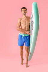 Handsome young man with board for sup surfing on color background