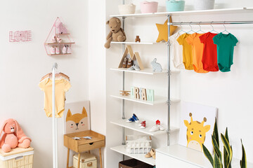 Interior of light children's room with toys and baby bodysuits