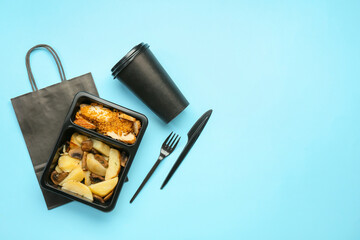 Food delivery container with tasty meals, paper bag, cup and cutlery on color background