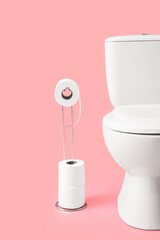 Holder with rolls of paper and toilet bowl on color background