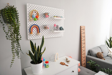 Pegboard with children's toys and bottles hanging on light wall in room