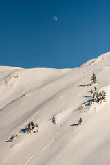 beautiful view of snowy mountain slope with freeride skiing tracks and blue sky